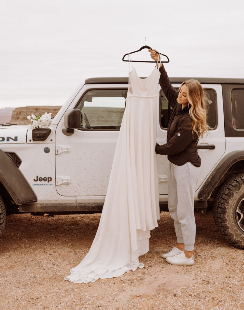 Bride holding dress at the jeep