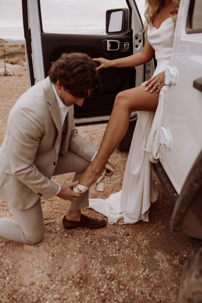 eloping groom helping bride put her shoes on
