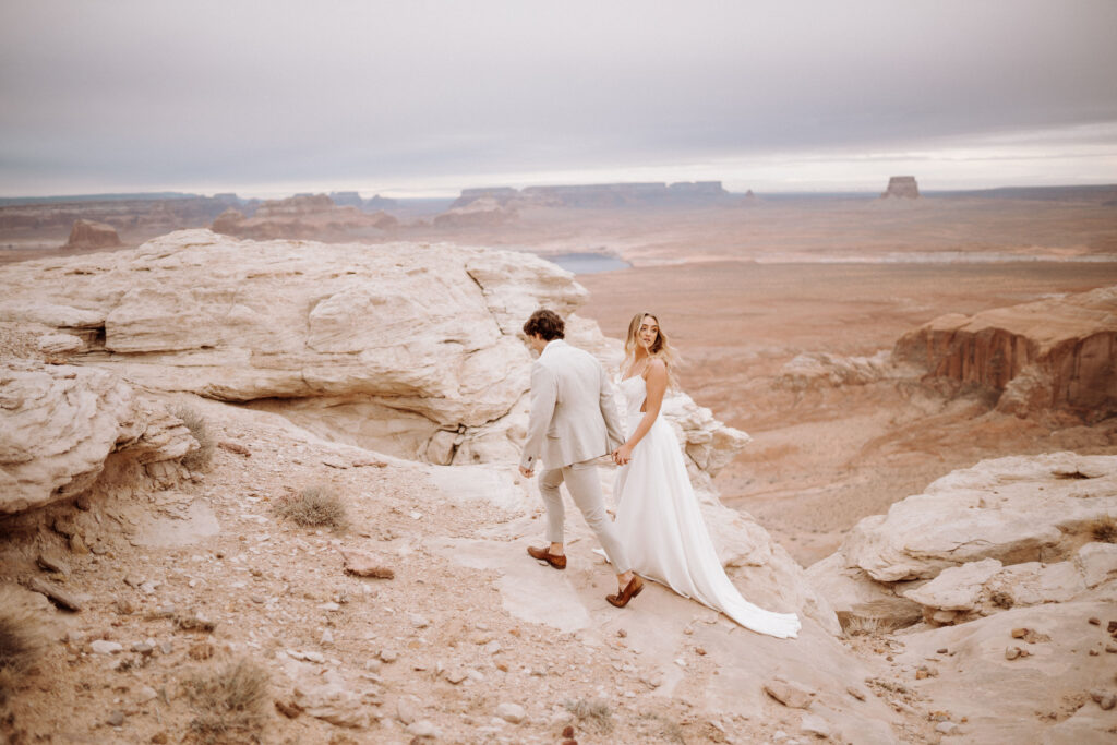 bride and groom walking on cliffs to photo spot for elopement photos