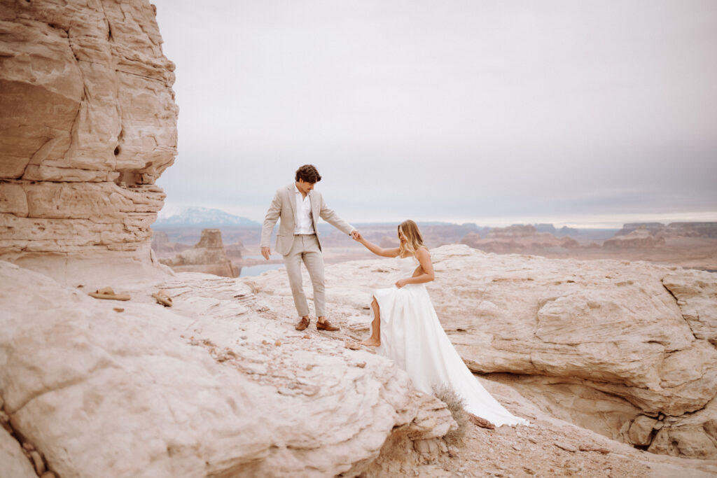 groom helping bride on cliffs