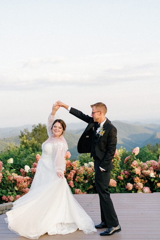 Couple dancing and twirling during portrait session after ceremony with mountain views in the back.