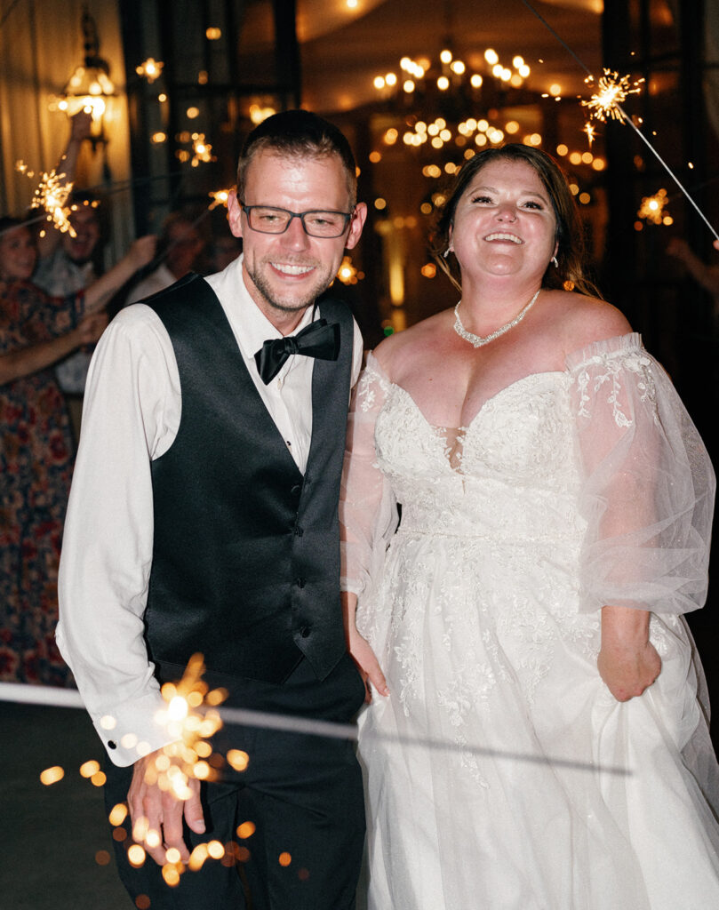 Bride and groom laughing during sparkle exit in the mountains.